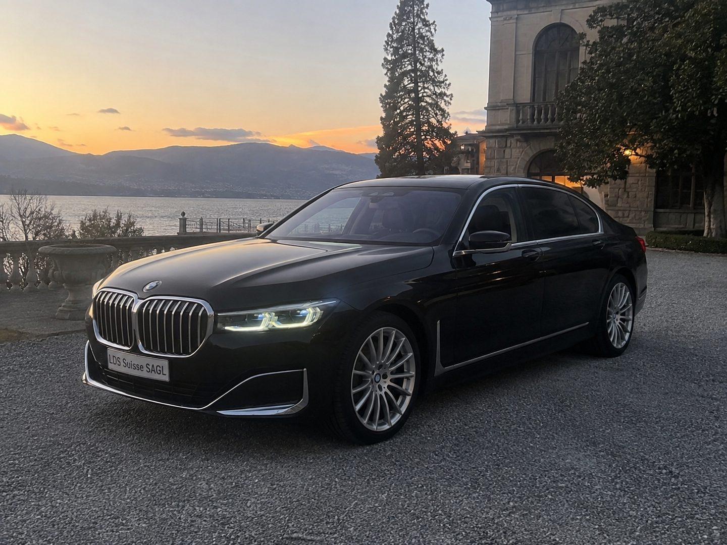 BMW Serie 7 davanti a una villa sul lago, al tramonto