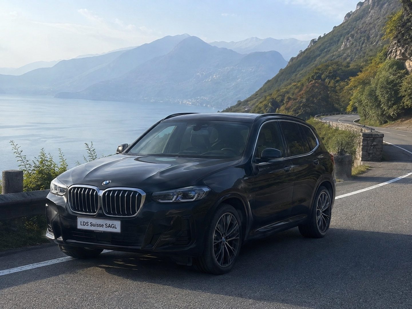 BMW X5 su una strada di montagna sopra il lago